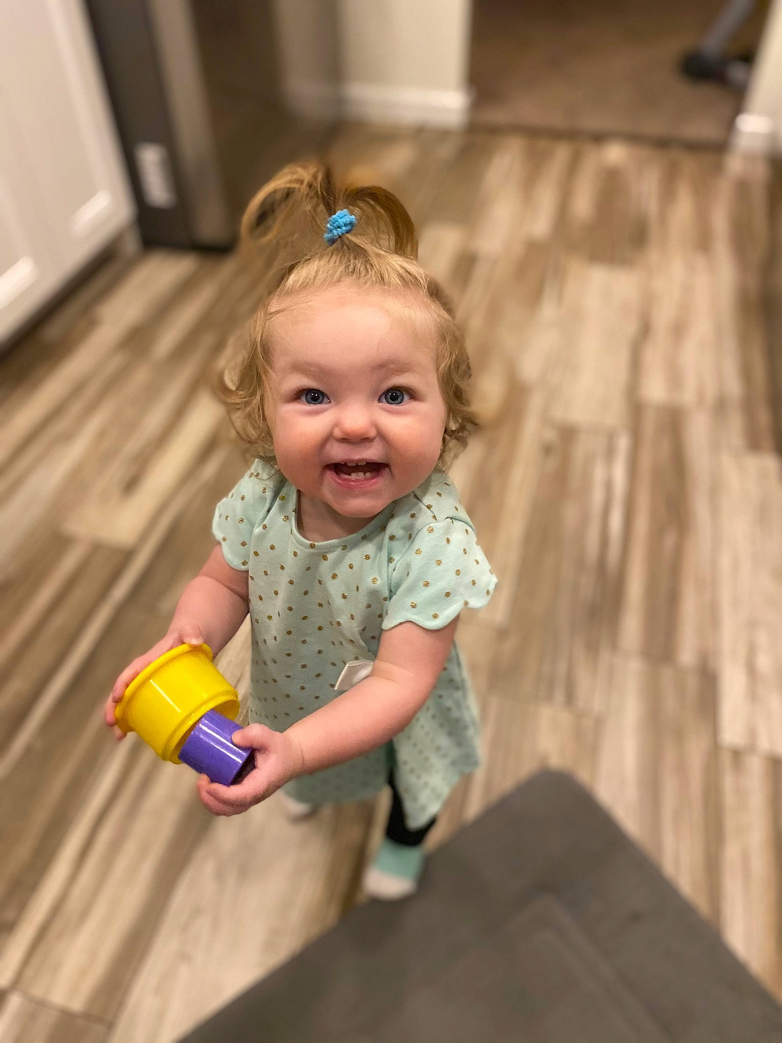 Olivia is registered to the contest to win money with this photo: baby_playing_with_toys, baby_toddler_clothing, cheek, child, eye, face, floor, flooring, fun, hairstyle, happy, iris, leisure, people, person, skin, smile, standing, toddler, toy