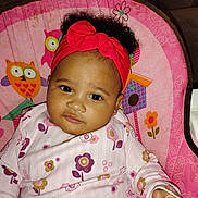 Anaya is registered to the contest to win money with this photo: baby, chair, child, colorful, curly_hair, cute, face, floral, flower, hand, headband, indoors, infant, looking, owl, pajamas, person, pink, portrait, seated