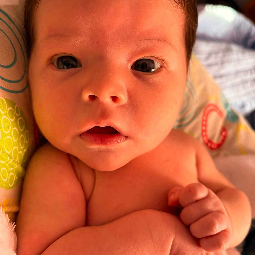 Skyler is registered to the contest to win money with this photo: baby, blanket, child, closeup, curious, cute, expression, eyes, face, hand, indoors, infant, newborn, pattern, person, portrait, skin, soft_light, wrapped, young