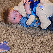 Samuel joined the competition — help win amazing prizes! big_eyes, blonde_hair, blue_shirt, book, boy, carpet, carpet_texture, child, cozy, family, home_interior, hugging, indoor, jeans, lying_down, playtime, plush_toy, teddy_bear, toddler, toy_tag