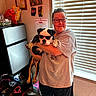bag, certificate, collar, dog, floor, glasses, holding, indoor, kitchen, light, pet, refrigerator, shadow, shorts, smiling, sunglasses, tshirt, wall_art, window_blinds, woman