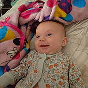 Hazel joined the competition — help win amazing prizes! baby, smiling, blanket, bed, floral_clothing, infant, happy, cute, lying_down, indoors, soft_texture, polka_dot, child, one_piece, portrait, face, cozy, colorful, young, comfort