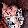 baby, blanket, couch, infant, person, face, clothing, expression, home, comfort, fabric, soft, cute, indoor, relaxing, child, pattern, warm, skin, portrait