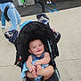 Isaiah is registered to the contest to win money with this photo: baby, stroller, child, smiling, outdoor, carnival, inflatable_toys, people, sidewalk, casual_clothing, happy, face, footwear, hand, toy, event, fun, daytime, urban, crowd