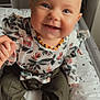 baby, child, smiling, blue_eyes, floral_top, olive_pants, hand_holding, sitting, cushion, stars_pattern, indoor, portrait, cute, happy, person, clothing, infant, face, head, baby_jewelry
