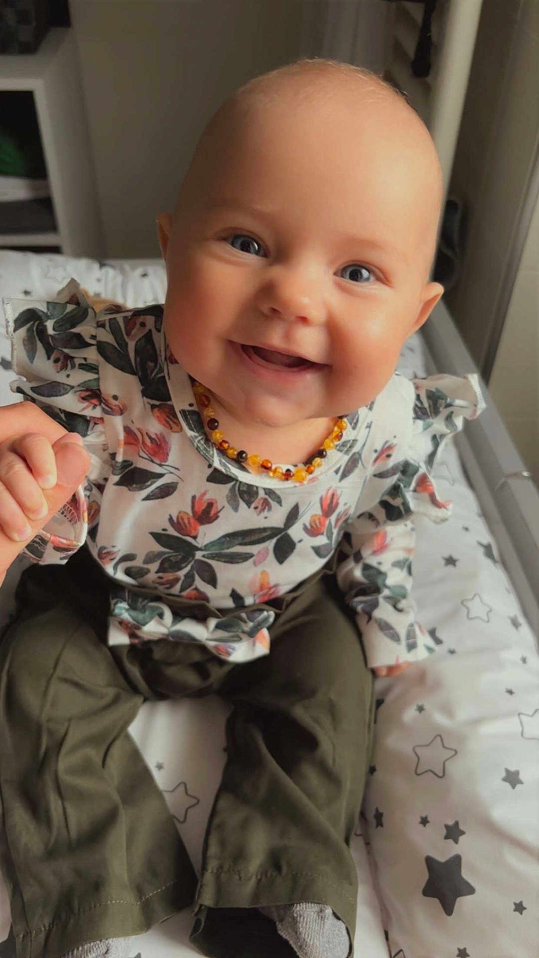 Naya participe au concours pour gagner de l'argent avec cette photo : baby, child, smiling, blue_eyes, floral_top, olive_pants, hand_holding, sitting, cushion, stars_pattern, indoor, portrait, cute, happy, person, clothing, infant, face, head, baby_jewelry