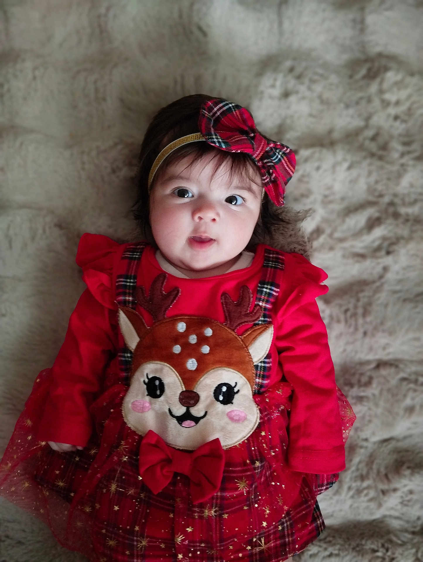 Emy a rejoint le concours — aidez-le/la à gagner de superbes lots ! adorable, baby, bow_headband, child, clothing, cute, expression, face, festive, holiday, indoors, infant, lying_down, plaid, portrait, red_dress, reindeer, smiling, soft_blanket, young_child