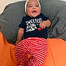 Maela joined the competition — help win amazing prizes! baby, bed, child, clothing, face, family, happy, headband, indoors, infant, lying_down, onesie, pillow, playful, portrait, red, sitting, smiling, striped_pants, white