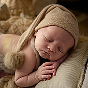 Léo participe au concours pour gagner de l'argent avec cette photo : baby, sleeping, hat, pom_pom, pillow, blanket, soft_texture, newborn, peaceful, cozy, infant, close_up, portrait, cute, resting, indoors, warm_colors, skin, hands, face