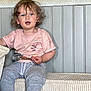 blue_eyes, casual_clothing, child, comfortable, couch, curly_hair, cute, expression, furniture, grey_pants, home, indoor, person, pink_shirt, relaxed, sitting, snack, toddler, wall_paneling, young_child
