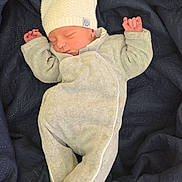 Léo a rejoint le concours — aidez-le/la à gagner de superbes lots ! baby, newborn, infant, sleeping_baby, knit_hat, onesie, grey_clothing, navy_blanket, quilt, cozy, tiny_hands, closed_eyes, portrait, indoors, soft_texture, cute, resting, newborn_photography, small_feet, peaceful