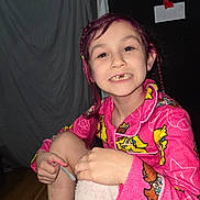 Davina is registered to the contest to win money with this photo: child, smiling, pink_hair, pajamas, tooth_loss, towel, nail_file, indoor, wooden_floor, curtain, wall, face, hand, happy, person, sitting, casual, portrait, home, cozy