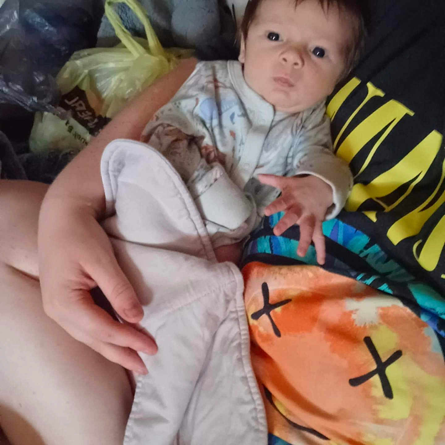 Dalton is registered to the contest to win money with this photo: arm, baby, blanket, bottle, casual, child, clothing, colorful, expression, fabric, face, hand, holding, indoor, pajamas, person, plush_toy, portrait, reaching_hand, sitting