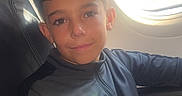 Bobby joined the competition — help win amazing prizes! airplane, airport, boy, casual, child, clothing, device, indoors, jacket, nike_logo, portrait, relaxed, seat, seatbelt, smile, sunlight, technology, travel, window, young