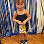 toddler, child, snack, black_dress, pigtails, indoor, wooden_floor, party_decor, streamers, shoes, black_and_white_shoes, standing, happy, cute, young_child, person, celebration, fun, background, hair