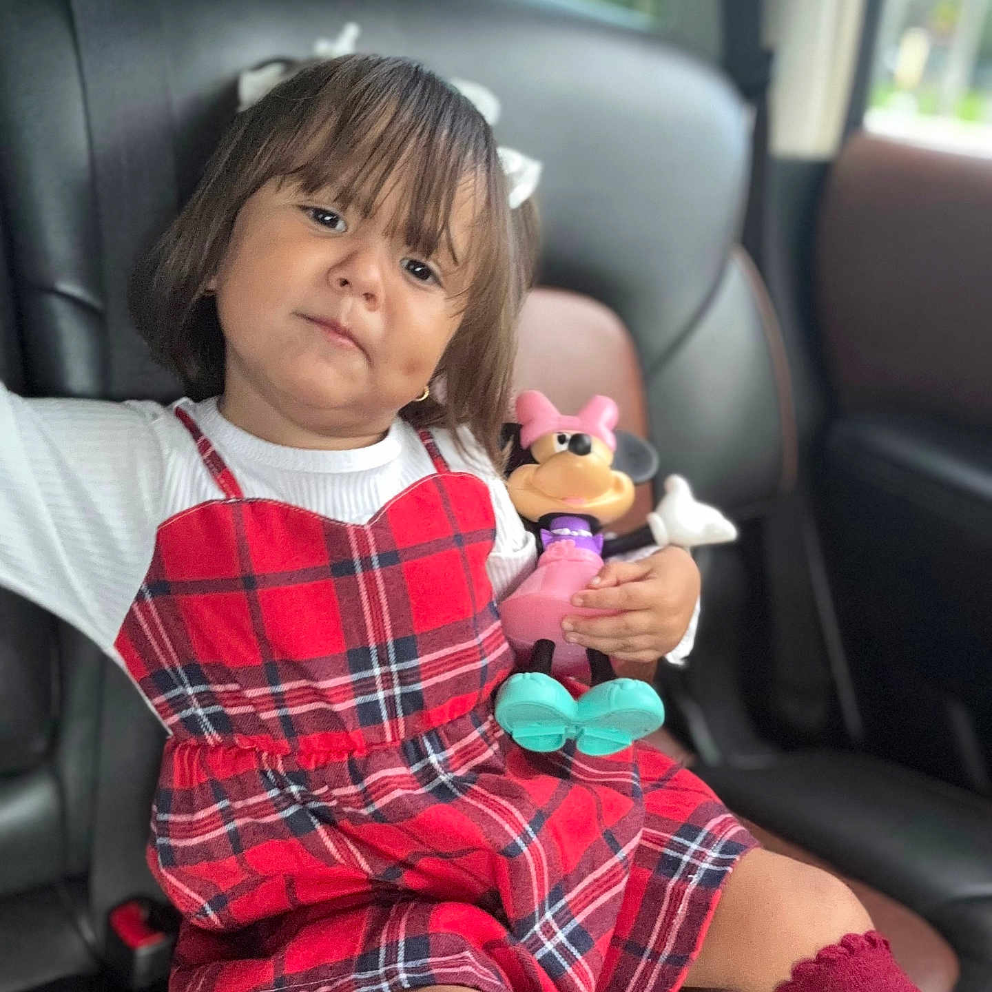 Alessia joined the competition — help win amazing prizes! car_interior, car_seat, child, cute, girl, hair_bow, indoor, kid, maroon_socks, minnie_mouse, person, plaid_dress, portrait, red, seat, sitting, toy, toy_figure, window, young_child