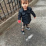Alessia is registered to the contest to win money with this photo: toddler, child, leather_jacket, plaid_pants, red_ball, sidewalk, pigtails, black_shoes, fence, tree_roots, outdoor, street, concrete, person, casual_clothing, young_child, curly_hair, urban, playful, holding_object