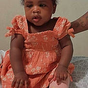 Kalayja joined the competition — help win amazing prizes! toddler, child, baby, dress, orange_dress, pink_socks, bows, hair_buns, tattooed_arm, bedspread, patterned_bedspread, sitting, indoor, person, cute, portrait, young_child, smiling, support, skin