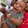 baby, smiling, striped_clothing, happy, infant, person, adult, holding, red_shirt, heart_pattern, bracelet, tattoo, portrait, outdoor, blurred_background, closeup, cute, joyful, skin, face