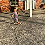Rocio joined the competition — help win amazing prizes! child, girl, dress, striped, cherry_pattern, sidewalk, concrete, brick_wall, door, window, plant, sunlight, shadow, smiling, walking, footwear, outdoor, daylight, holding_food, happy