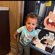 Destin joined the competition — help win amazing prizes! toddler, child, curly_hair, smiling, birthday_shirt, indoor, cartoon_poster, panda, reflection, glass_door, happy, clothing, pants, floor, cabinet, wood, person, cute, portrait, playful
