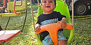 Jayden participe au concours pour gagner de l'argent avec cette photo : child, toddler, swing, playground, grass, sunlight, outdoor, happy, smiling, green, orange, tree, person, summer, fun, recreation, seat, barefoot, clothing, nature