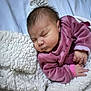 newborn, baby, sleeping, blanket, purple_clothing, infant, bed, soft_texture, peaceful, closeup, indoor, child, resting, cute, portrait, young, cozy, warm, small_hands, relaxed