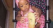 Genesis is registered to the contest to win money with this photo: baby, child, stroller, pink_dress, headband, shoe, polka_dots, indoor, floor, curious, seated, footwear, person, toddler, fabric, pattern, toy, hand, face, infant
