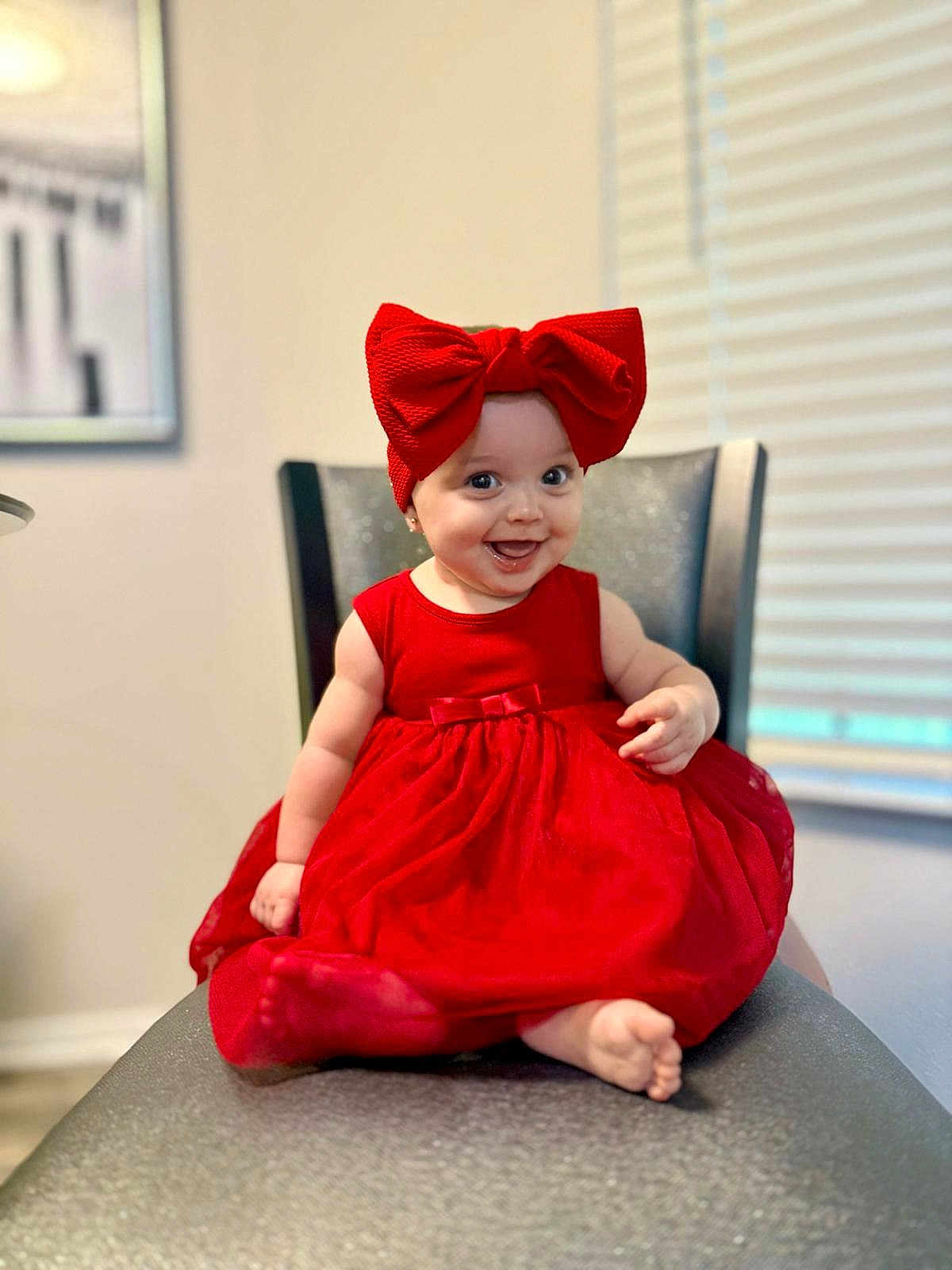 Elena is registered to the contest to win money with this photo: baby, child, red_dress, headband, bow, smile, happy, sitting, chair, indoor, cute, portrait, infant, clothing, feet, person, fashion, adorable, fun, bright