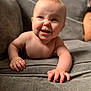 baby, crawling, smiling, face, hand, arm, couch, gray, indoor, child, cute, skin, expression, happy, infant, person, furniture, home, tongue, young