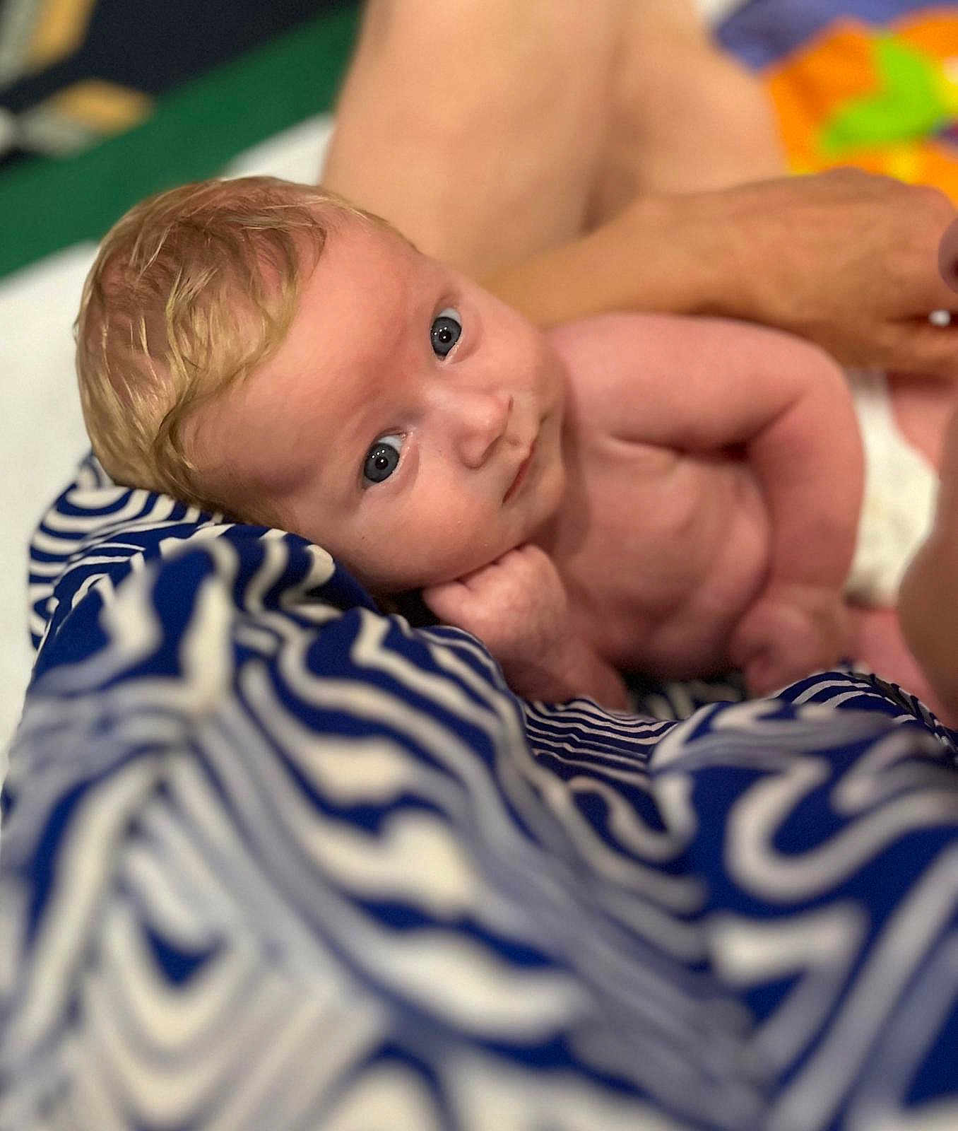 Zayn participe au concours pour gagner de l'argent avec cette photo : baby, infant, blue_eyes, blanket, patterned_blanket, skin, arm, hand, person, resting, curious, close_up, portrait, indoor, soft_light, head, face, newborn, support, human