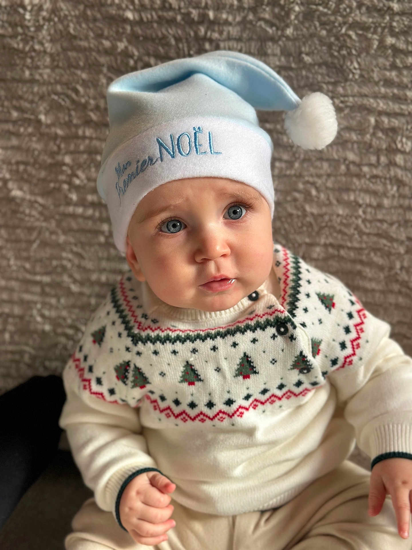 Stefan a rejoint le concours — aidez-le/la à gagner de superbes lots ! baby, child, blue_eyes, christmas_hat, santa_hat, festive_clothing, sweater, knitwear, pattern, holiday, cute, portrait, indoors, soft_lighting, seated, expression, face, hands, winter, warm_clothing
