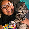 Tigger is registered to the contest to win money with this photo: child, girl, glasses, smile, happy, cat, kitten, pet, tabby, indoor, couch, cushion, colorful, shirt, closeup, portrait, holding, whiskers, bell, feline