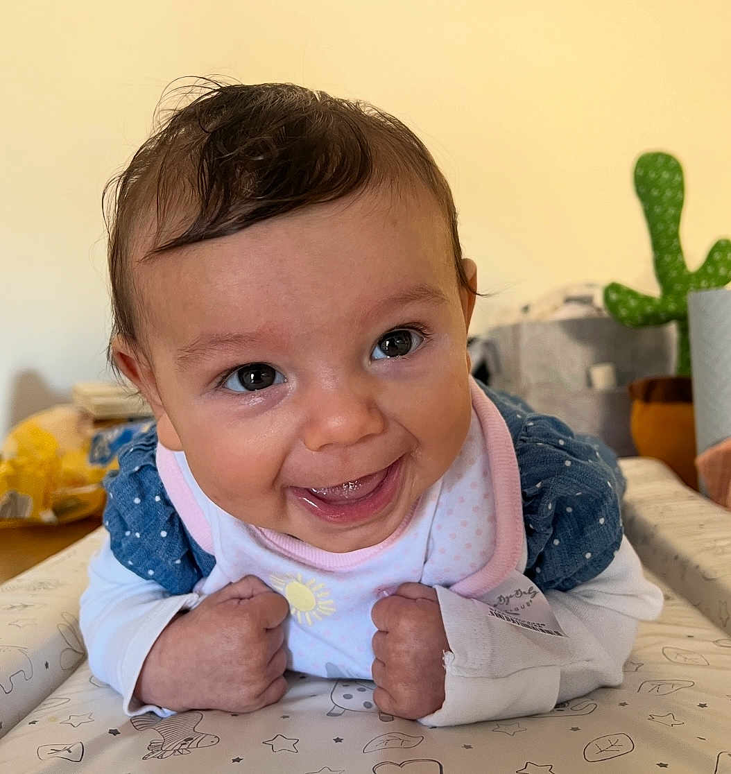 Penny joined the competition — help win amazing prizes! baby, smiling, face, infant, cute, happy, indoor, toddler, clothing, bib, polka_dots, hands, eyes, expression, cactus, background, table, pattern, skin, portrait