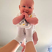 Carson is registered to the contest to win money with this photo: baby, infant, hands, feet, legs, smile, happy, person, white_clothing, socks, indoor, skin, face, arms, playful, holding, light, background, human, cute