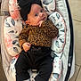 baby, infant, child, black_bow, leopard_print, pants, socks, baby_seat, floral_pattern, cushion, indoor, floor_tiles, cute, portrait, person, young_child, comfort, resting, clothing, headwear