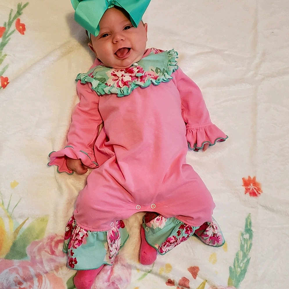 Blakelynn is registered to the contest to win money with this photo: baby, baby_products, baby_toddler_clothing, child, costume, flower, pattern, peach, person, pink, plant, product, rose, ruffle, sleeve, textile, toddler