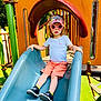 child, slide, playground, sunglasses, cap, shorts, tshirt, shoes, outdoor, summer, fun, play, park, toy, equipment, greenery, daylight, person, fashion, leisure