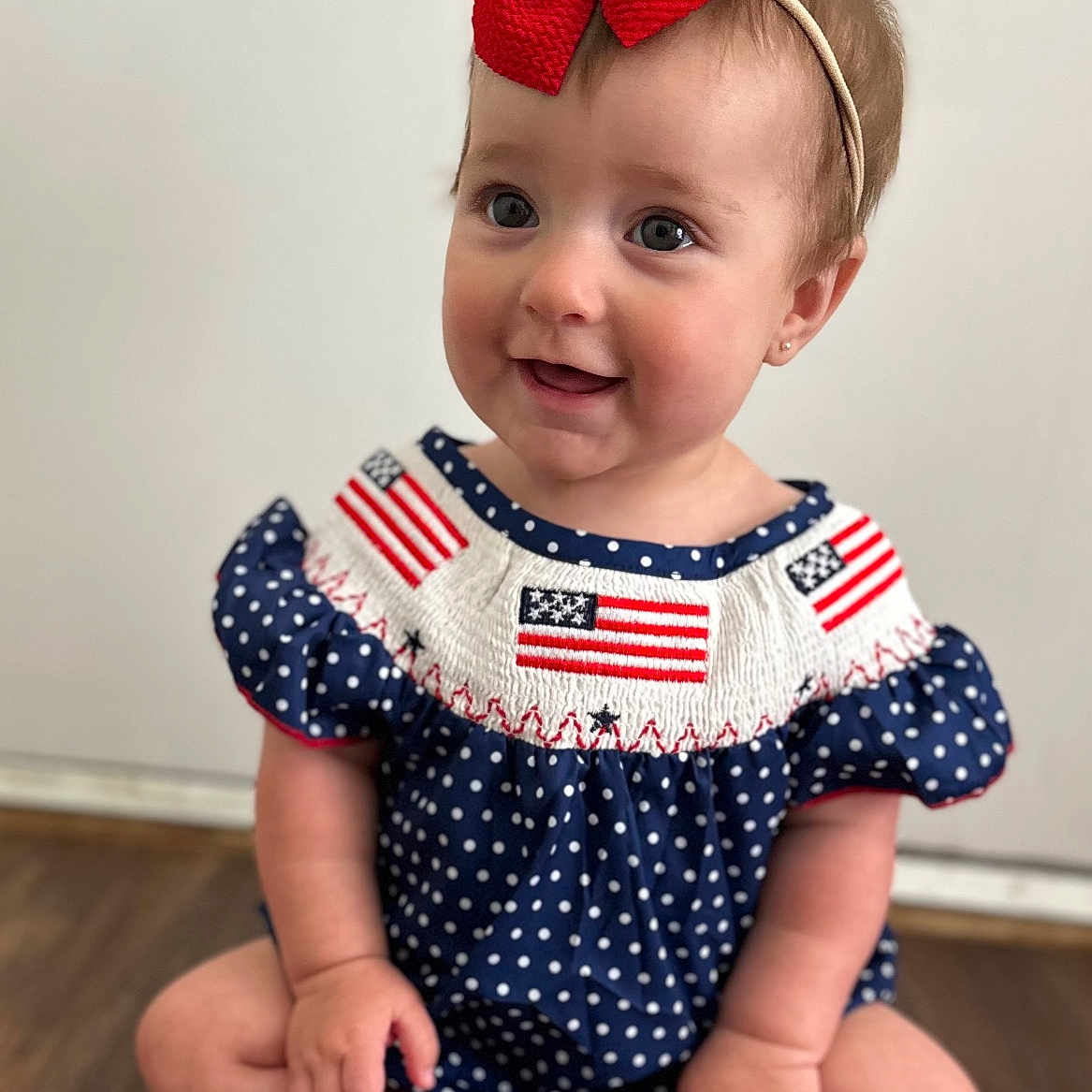 Emberlynn joined the competition — help win amazing prizes! baby, child, cute, dress, face, feet, floor, girl, hands, happy, headband, indoor, infant, polka_dot, portrait, red_bow, sitting, skin, smile, wooden_floor