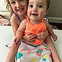 child, baby, smiling, hugging, bed, clothing, orange_top, skirt, popsicle_pattern, indoor, happy, cute, person, family, siblings, portrait, candid, young_children, barefoot, playful