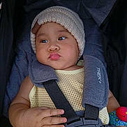 Zyron is registered to the contest to win money with this photo: baby, infant, child, portrait, stroller, car_seat, knit_hat, winter_clothing, serious_expression, pout, face, eyes, hands, sitting, harness, straps, toy, colorful, indoor, close_up