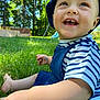 toddler, child, smiling, grass, outdoor, blue_hat, striped_shirt, sunlight, happy, greenery, playground, nature, baby, cute, summer, person, portrait, daylight, cheerful, sitting