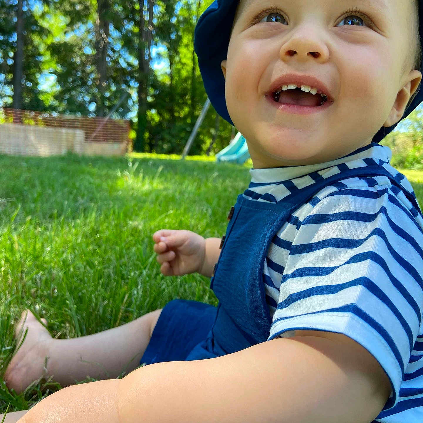 Eliott participe au concours pour gagner de l'argent avec cette photo : baby, blue_hat, cheerful, child, cute, daylight, grass, greenery, happy, nature, outdoor, person, playground, portrait, sitting, smiling, striped_shirt, summer, sunlight, toddler