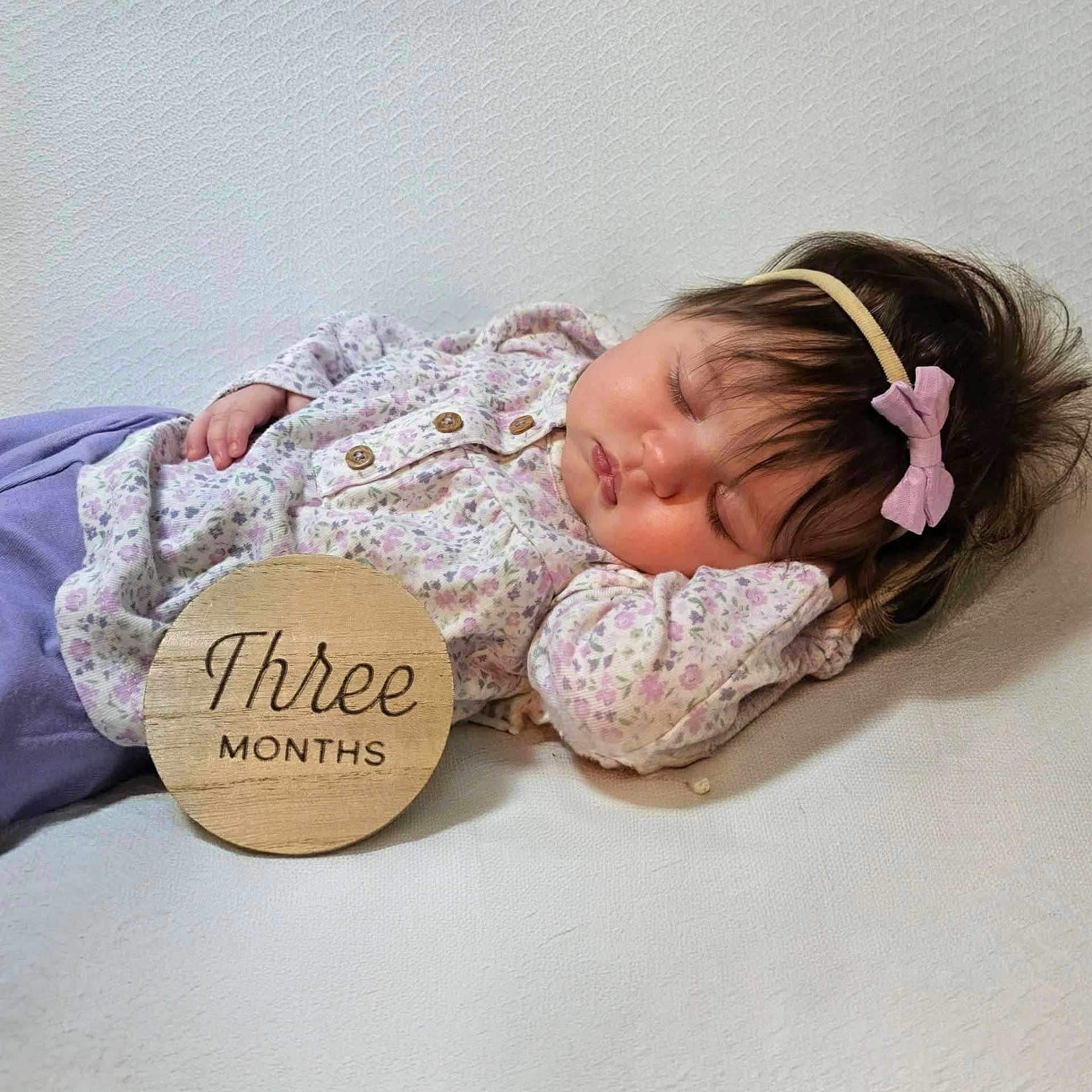 Scotlynne May is registered to the contest to win money with this photo: adorable, baby, bow, calm, child, closeup, cute, floral_pattern, headband, indoors, infant, newborn, peaceful, portrait, purple_clothing, resting, sleeping, soft_surface, three_months, wooden_sign