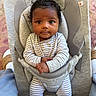 baby, infant, child, baby_rocker, striped_pajamas, gray_fabric, indoor, portrait, curly_hair, wide_eyes, seat, baby_seat, cute, small_hands, comfort, soft_lighting, looking_at_camera, baby_clothing, infant_care, home