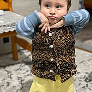Muhammad joined the competition — help win amazing prizes! carpet, chair, child, clothing, cute, expression, funny_face, home, indoor, leopard_print, long_sleeve, mickey_mouse, pattern, person, playful, shorts, standing, table, vest, yellow_shorts
