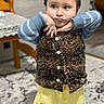 carpet, chair, child, clothing, cute, expression, funny_face, home, indoor, leopard_print, long_sleeve, mickey_mouse, pattern, person, playful, shorts, standing, table, vest, yellow_shorts