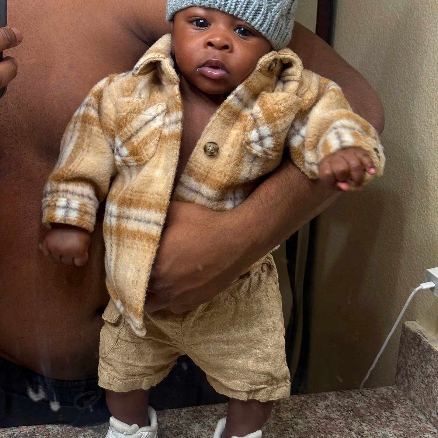 Kasai is registered to the contest to win money with this photo: baby, child, hat, pom_pom, jacket, plaid, shorts, sneakers, white_shoes, standing, bathroom, countertop, mirror, hand, person, indoor, portrait, cute, warm_clothing, expression