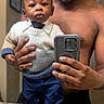 baby, child, man, mirror, selfie, smartphone, sweater, tie, pants, shoes, bathroom, sink, countertop, hand, portrait, indoor, reflection, fashion, cute, person