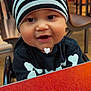 Ryker joined the competition — help win amazing prizes! baby, child, striped_hat, black_clothing, skeleton_print, table, red_table, indoor, restaurant, high_chair, cute, smiling, face, headwear, person, young_child, seated, happy, closeup, curious